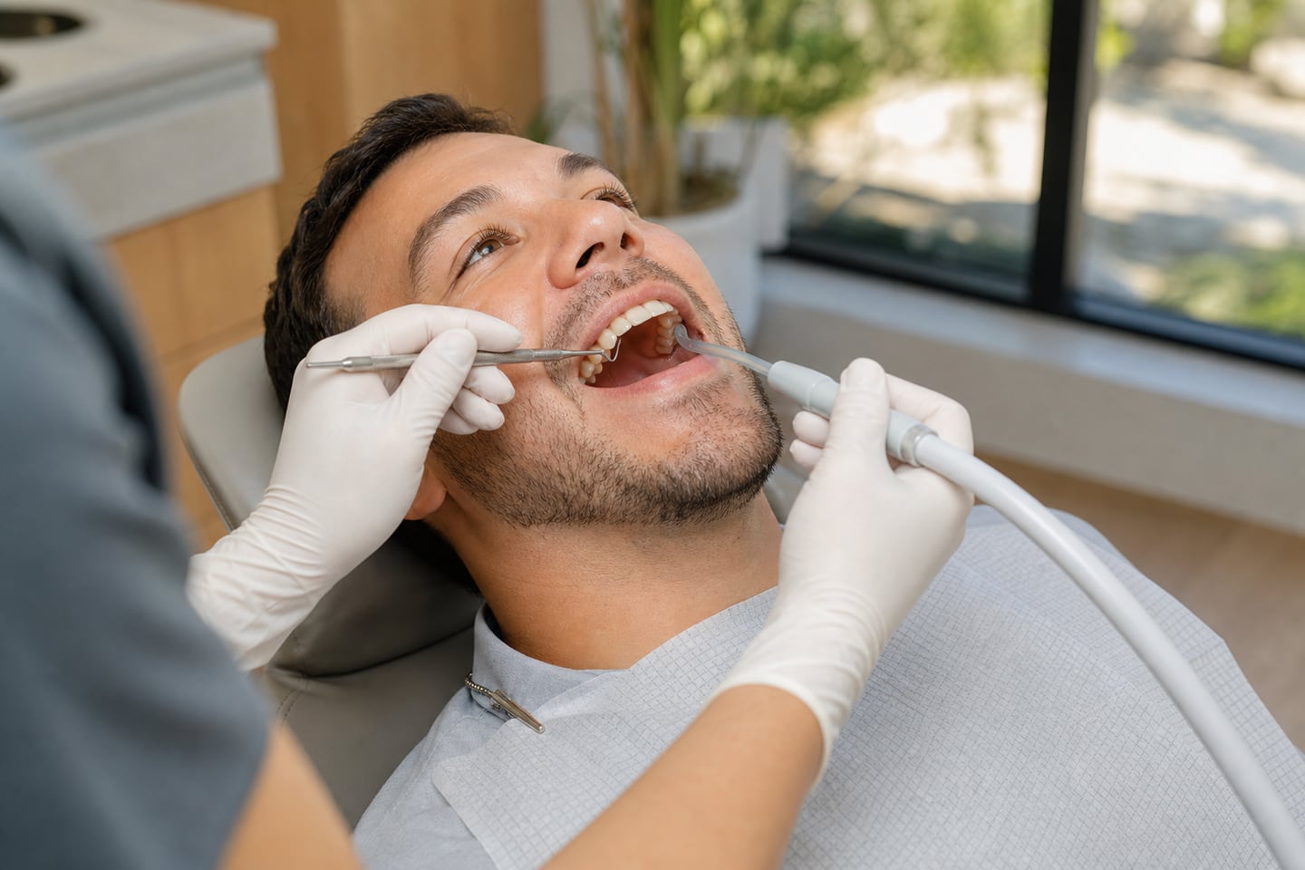 A dental hygienist cleaning a patient's teeth during a routine hygiene appointment.