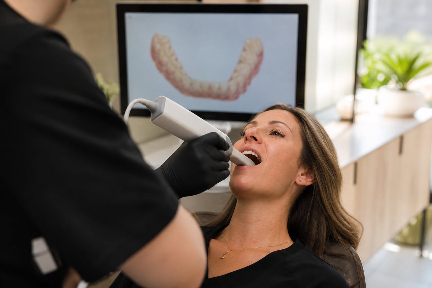 A dentist using a handheld intraoral scanner during a digital scan.