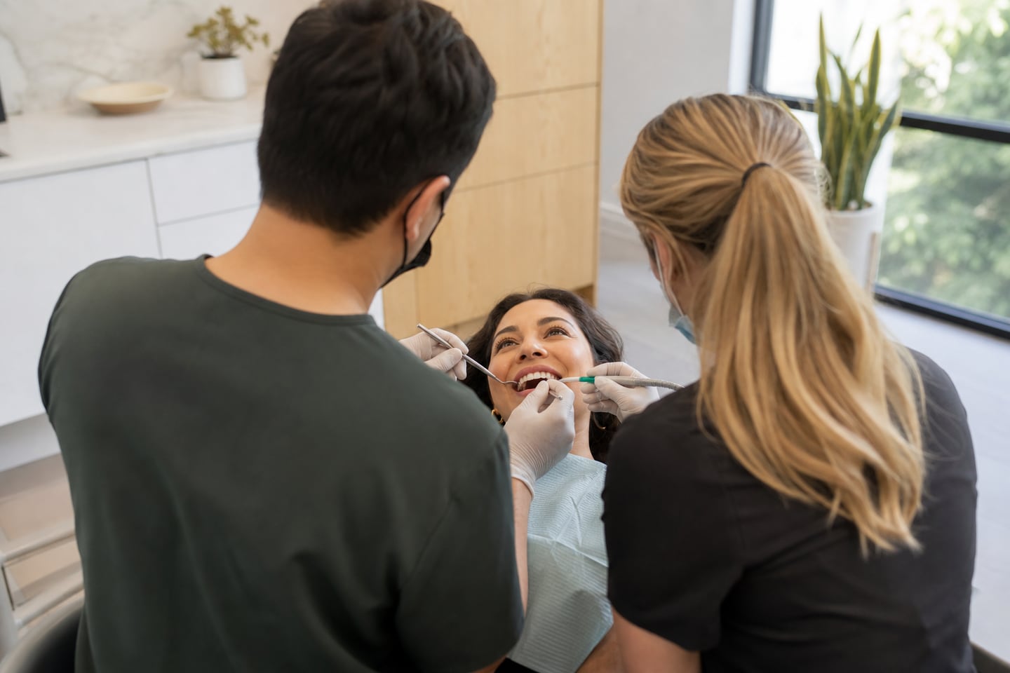 A dentist and assistant carrying out a restorative treatment on a calm patient.